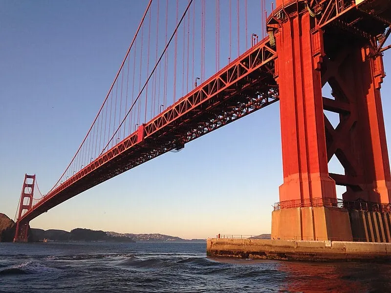 The Golden Gate Bridge viewed from beneath the south tower at golden hour — Odin Systems provides mobile and permanent video security across the San Francisco Bay Area.