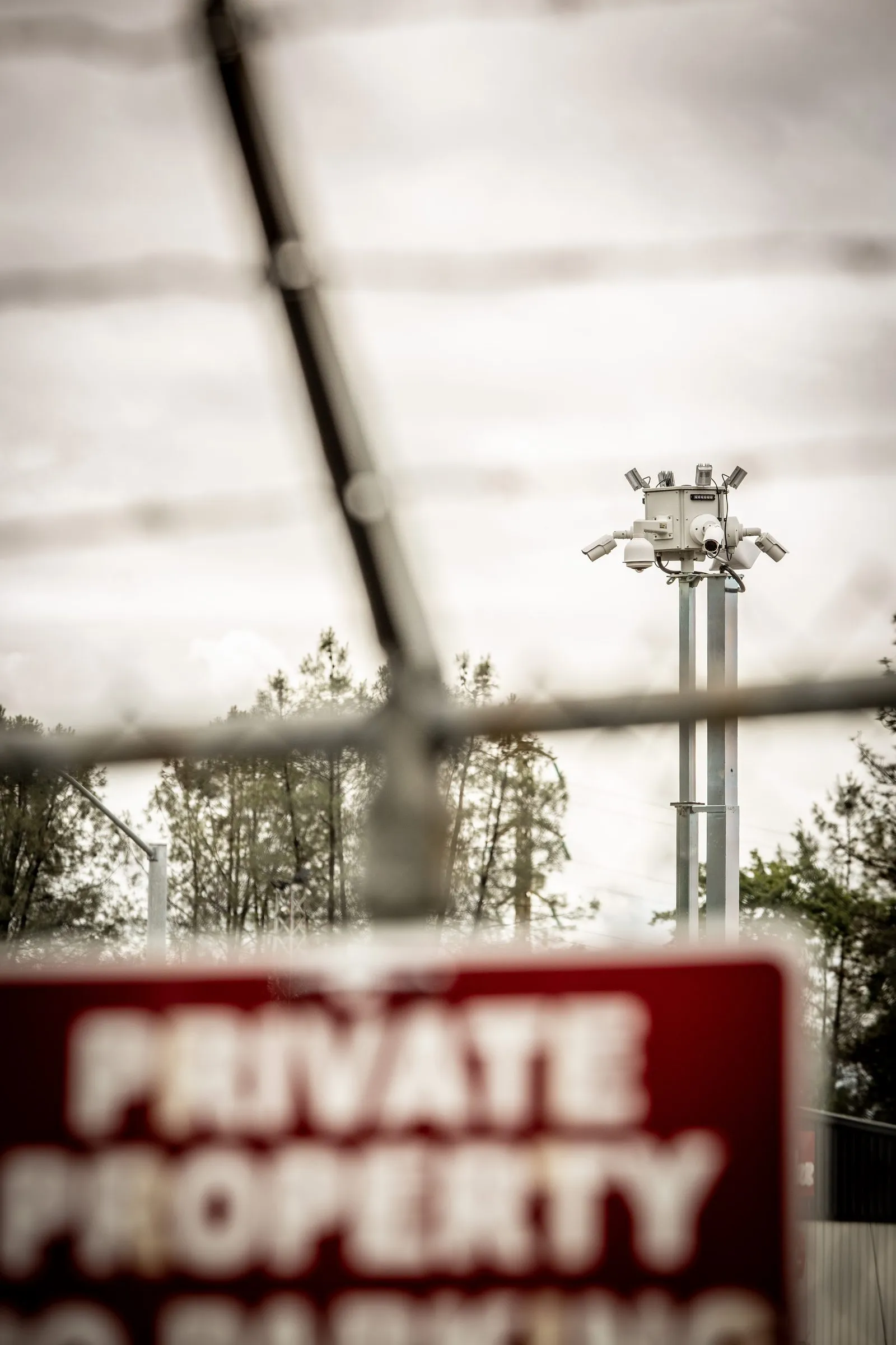 A multi-camera Odin Systems surveillance pod raised on a mast overlooks a fenced construction site, viewed past a red Private Property sign — rapid-deploy jobsite security.