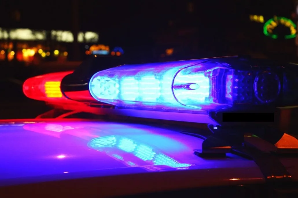 Red and blue emergency light bar illuminated atop a police vehicle at night.