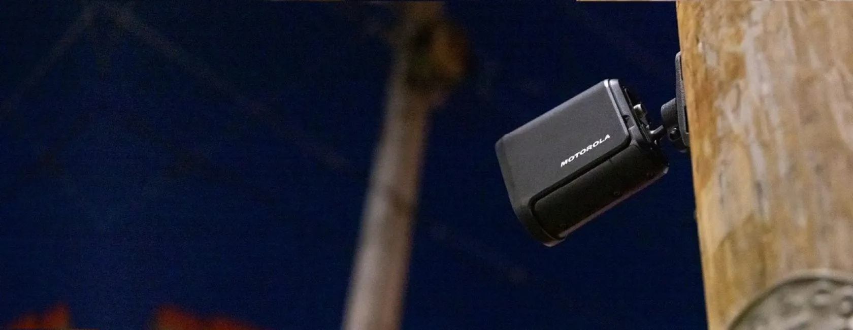 A Motorola license-plate-recognition camera mounted on a utility pole at dusk in a residential neighborhood.