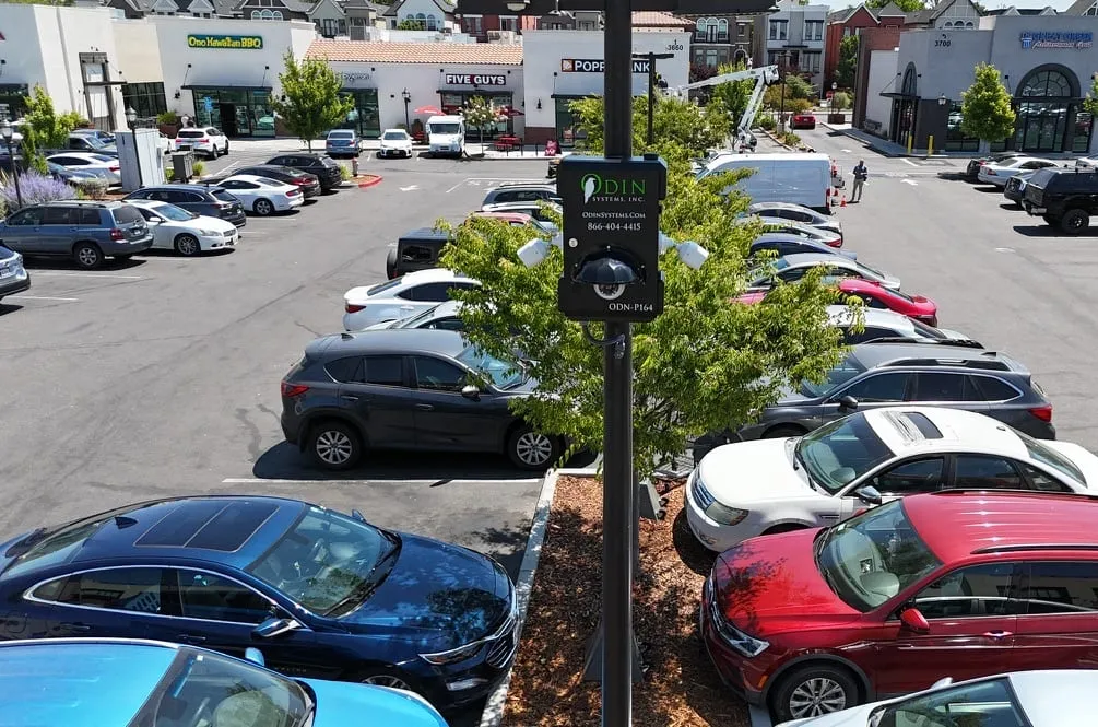 An Odin Systems RVN Pod camera station mounted on a pole, overlooking a busy shopping-center parking lot.