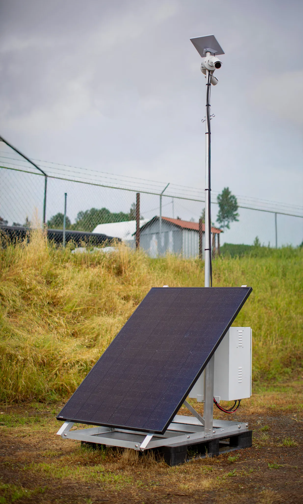 Odin Systems Solar RVN Pod — a freestanding solar-powered surveillance tower with camera and solar panel, deployed at a fenced site.